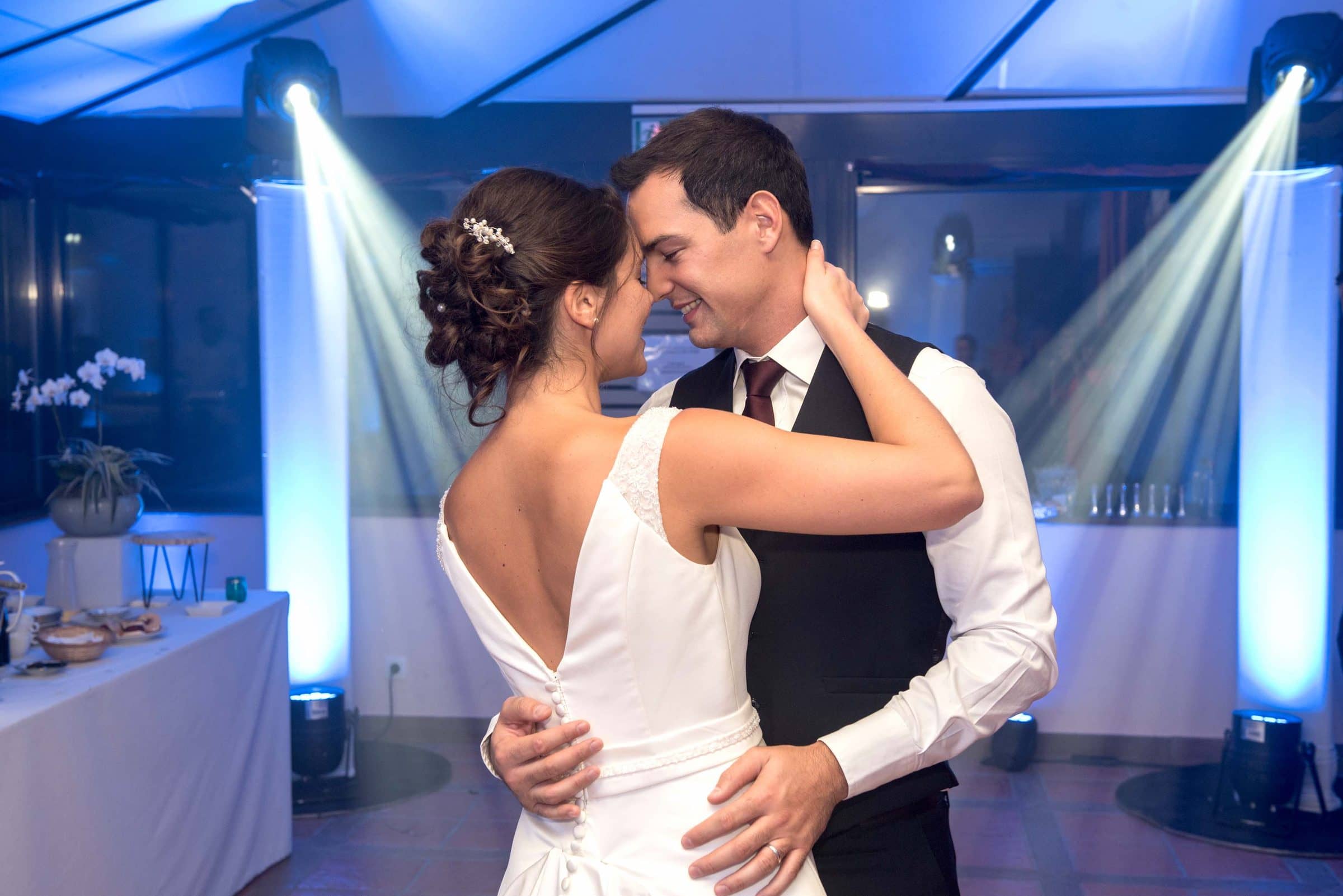 Newlyweds embracing on the dance floor between two columns of light
