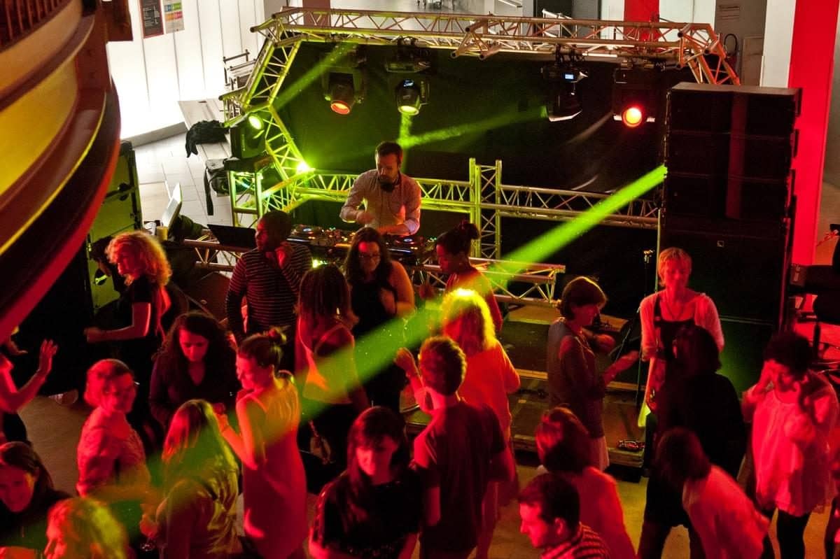 Public qui danse devant une régie DJ sur scène