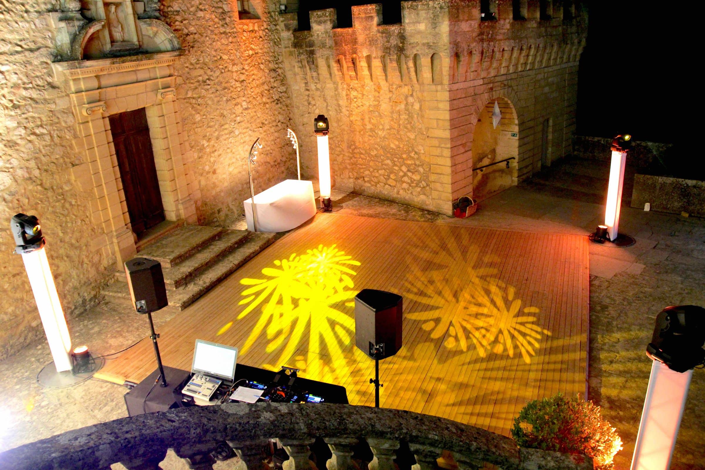 Cour de château préparée pour la soirée : enceintes, colonnes lumineuses et piste éclairée