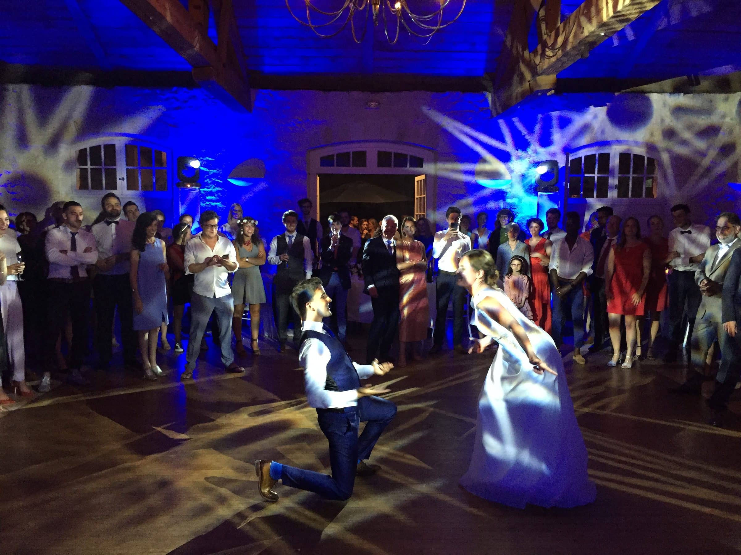 Première danse des mariés sous des projections lumineuses bleues, entourés des invités