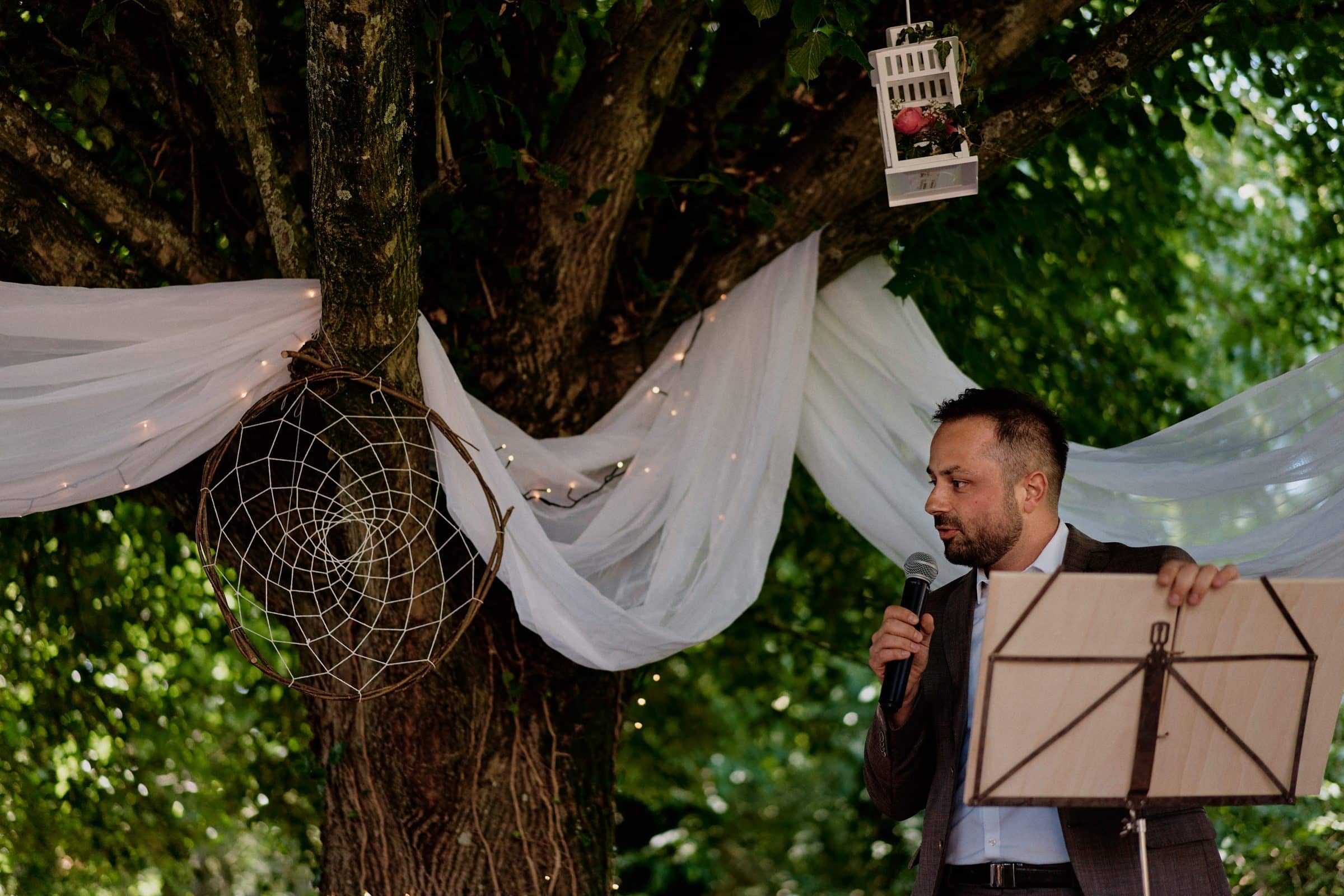 Celebrant speaking into a microphone at an outdoor ceremony