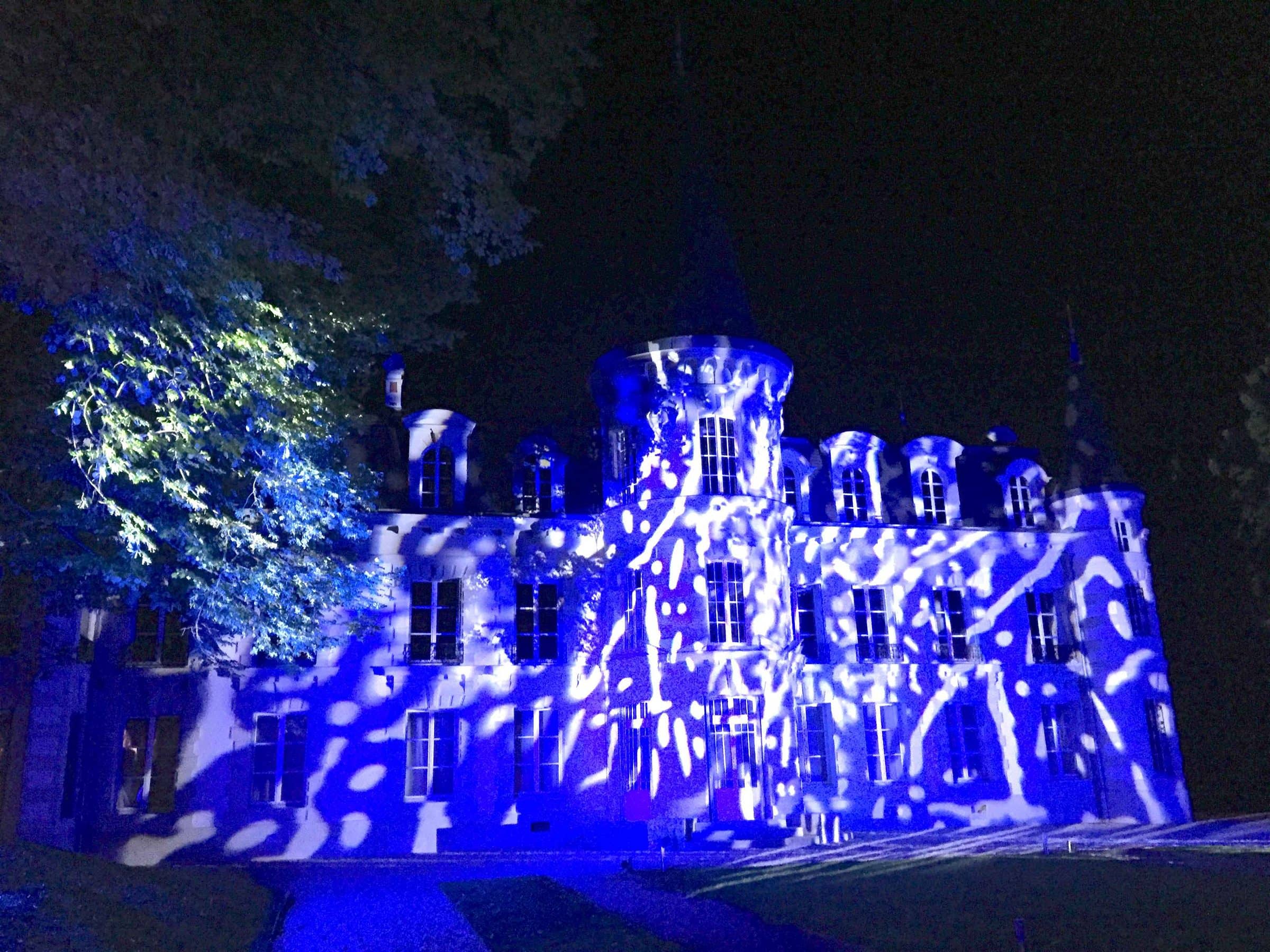 Façade de château illuminée de motifs lumineux bleus