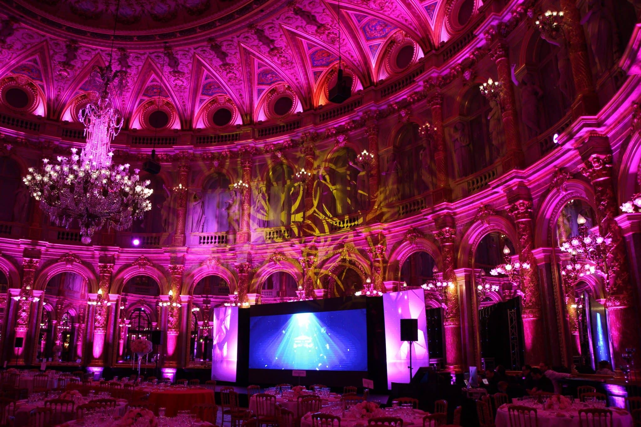 Dîner de gala dans une salle historique éclairée en rose et violet