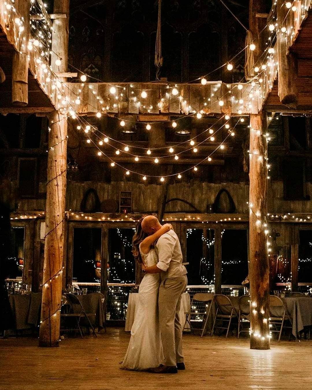 Newlyweds dancing under a canopy of string lights in a barn