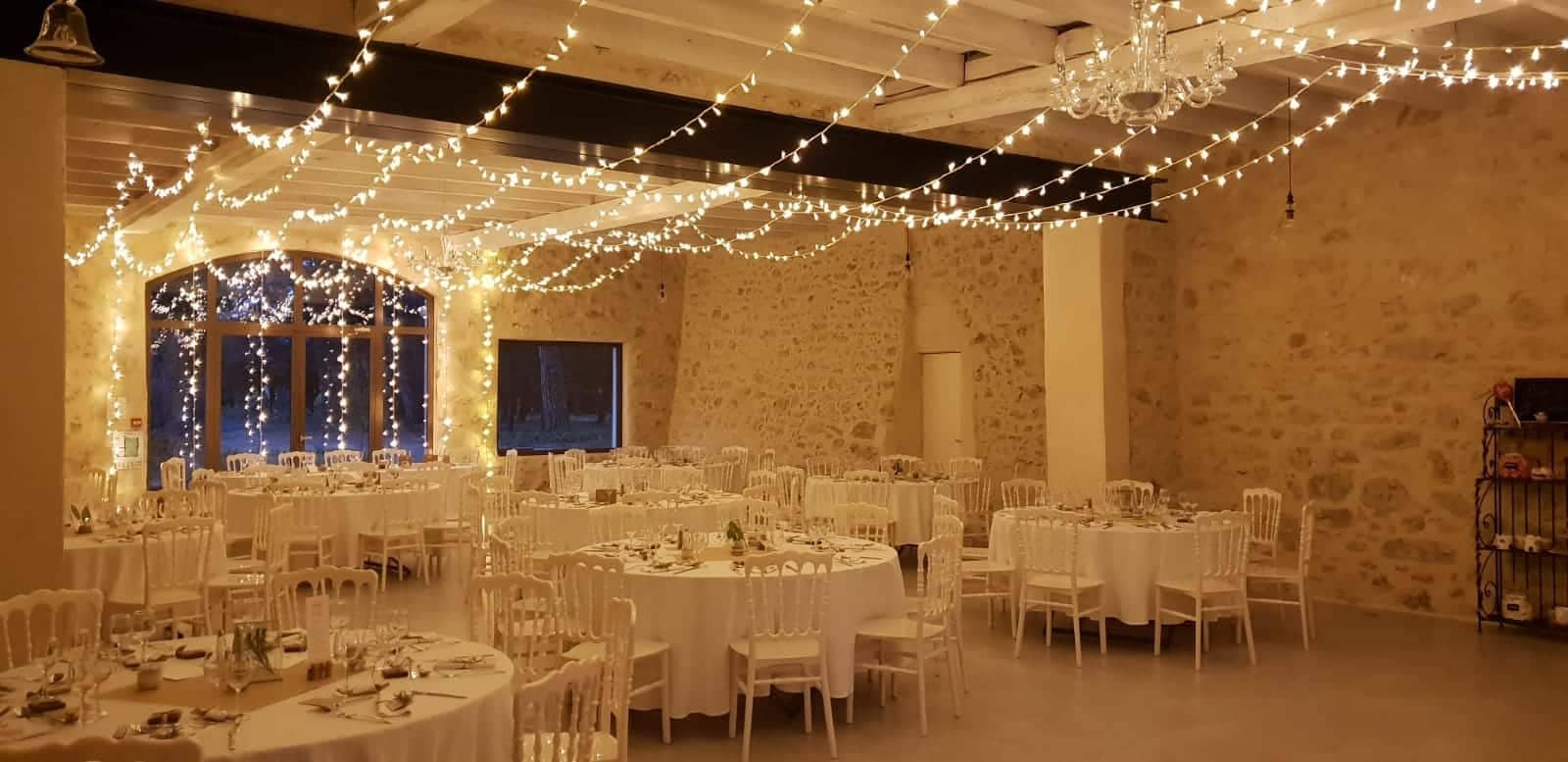 Stone hall lit by string lights above the tables