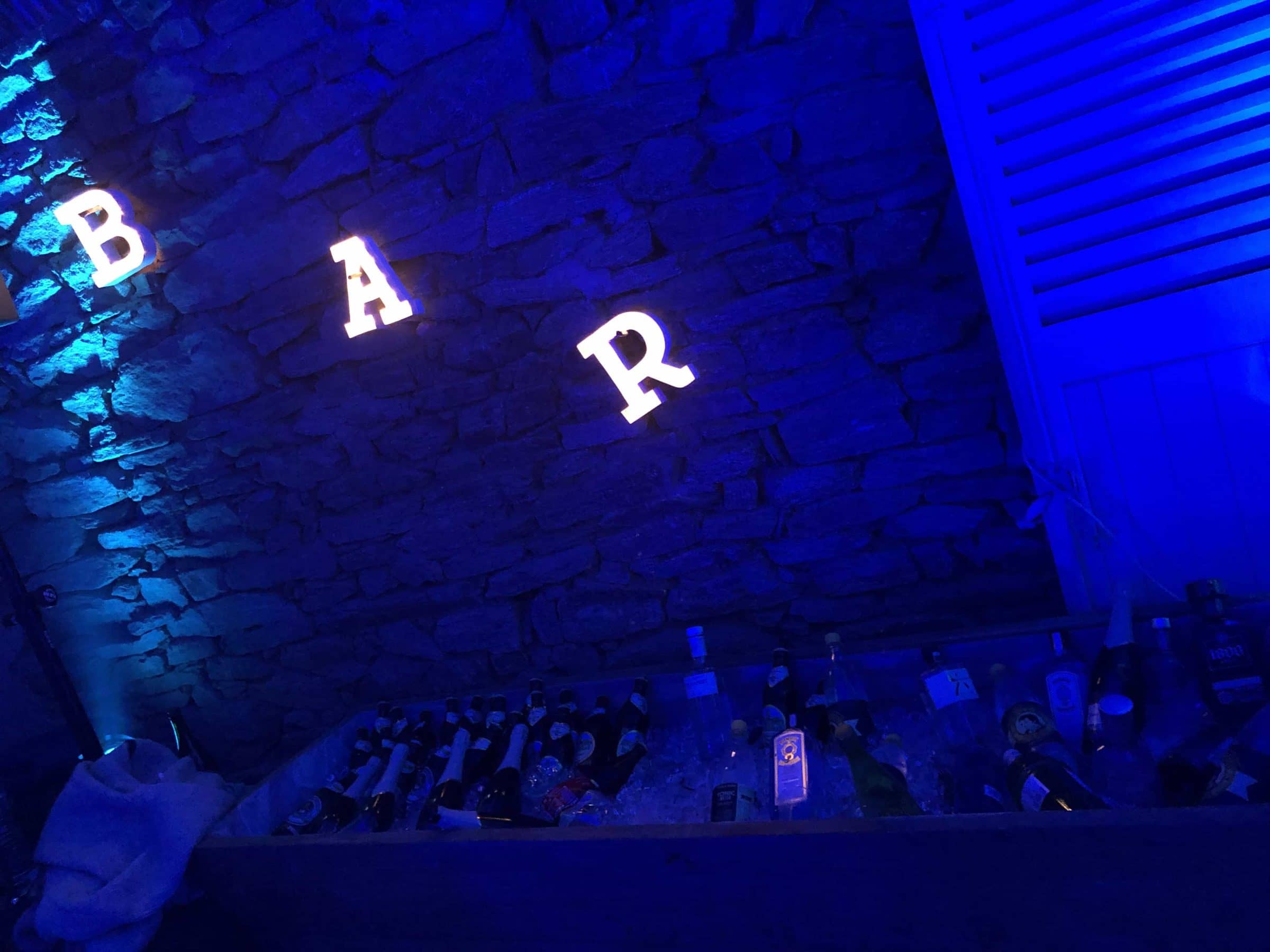 Lettres lumineuses « BAR » sur un mur éclairé en bleu