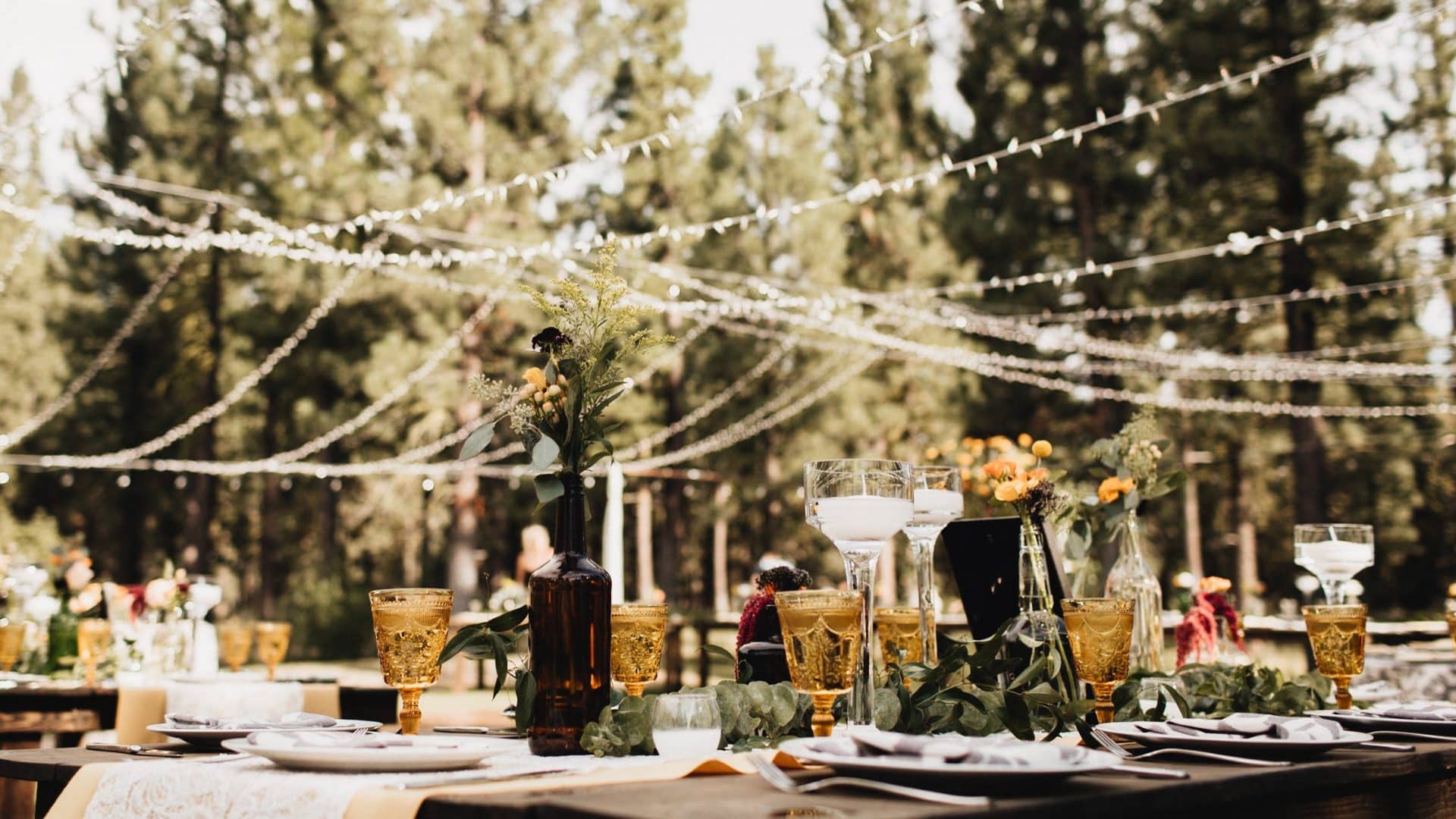 Table de mariage champêtre sous des guirlandes en forêt