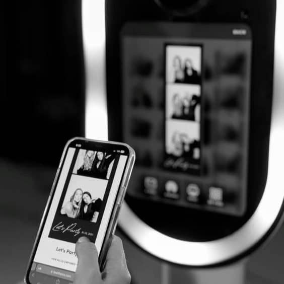 Invité tenant son tirage devant la borne photobooth, en noir et blanc