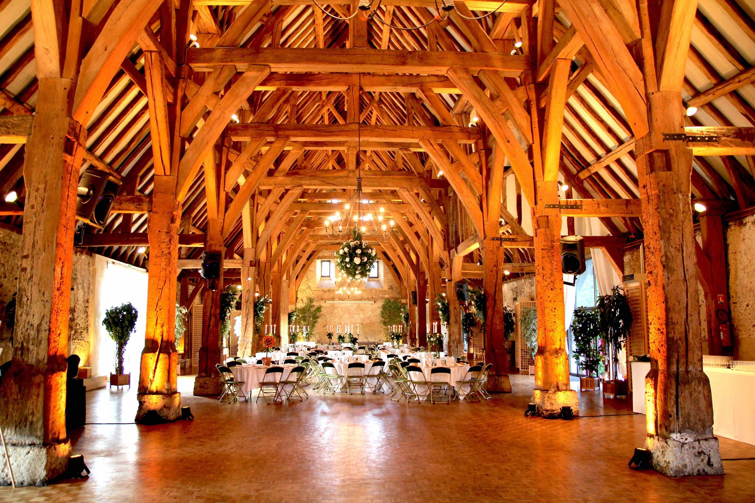 Grande salle à charpente en bois mise en lumière pour un dîner de mariage