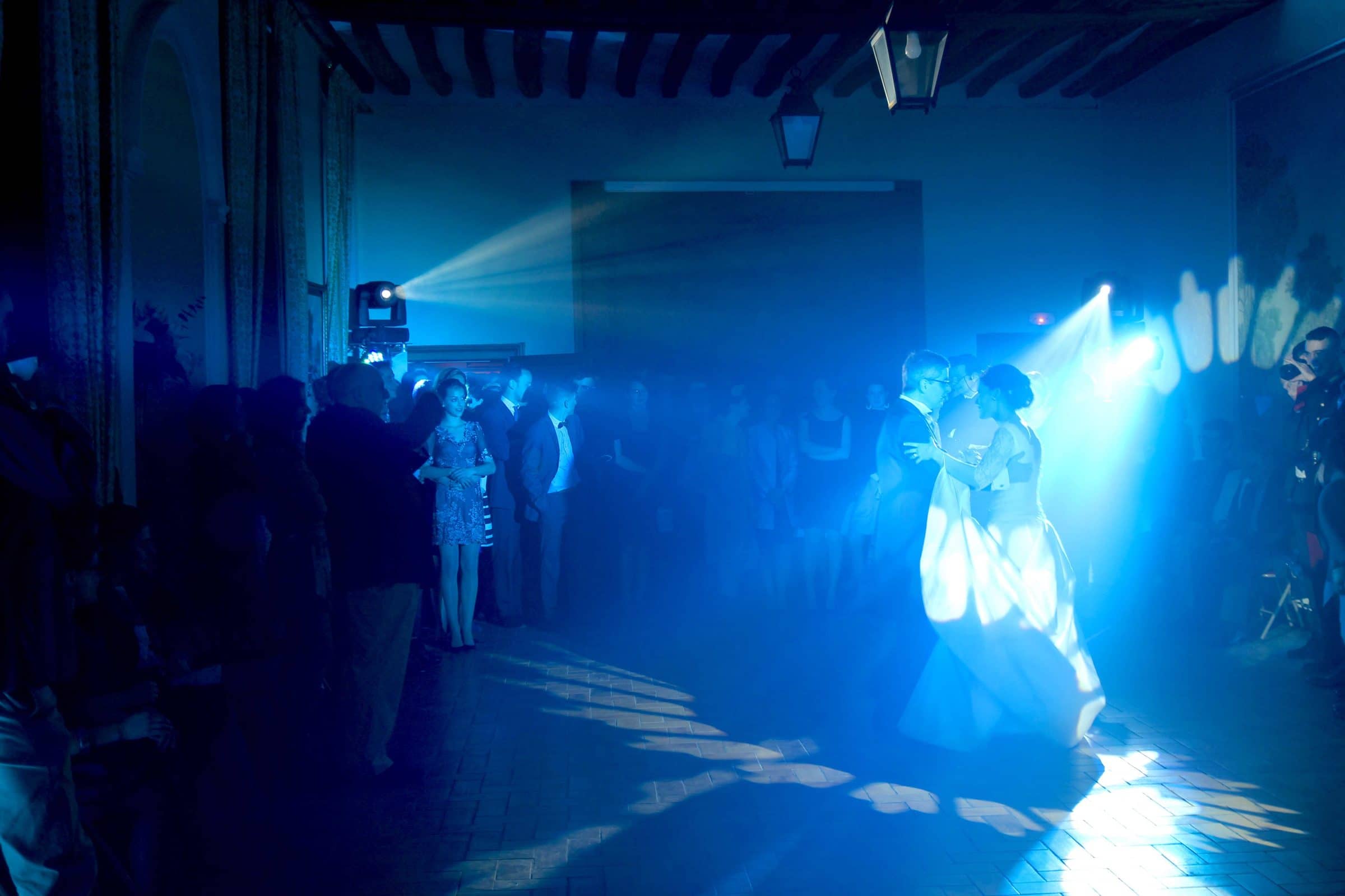 Newlyweds opening the dance in haze under blue light