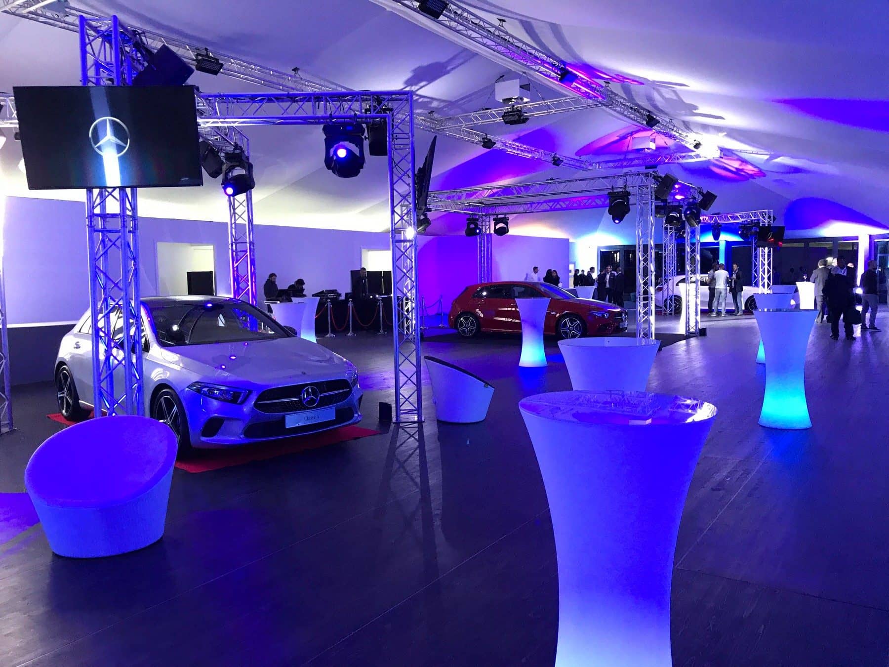 Salle d'exposition éclairée en bleu, voitures et mange-debout lumineux