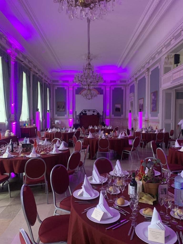 Salle de réception éclairée en violet avec tables dressées